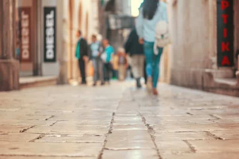 Melbourne shopping laneways. Lady in jeans walking down a cobblestone laneway with fashion boutiques.
