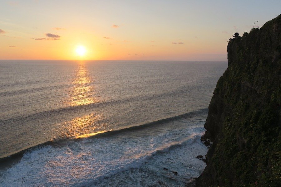 Sunset over the ocean in Bali with Uluwatu temple in foreground