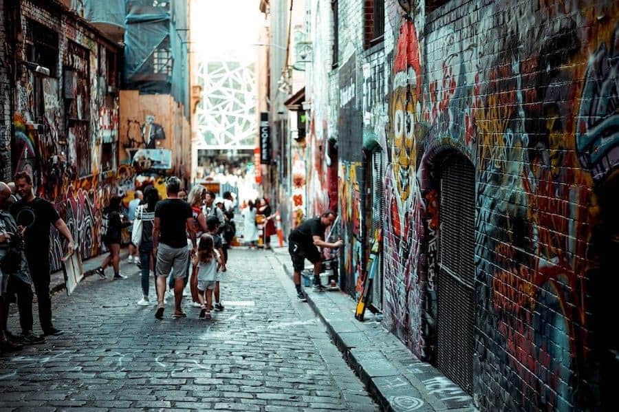 Hosier Lane in Melbourne. People walking down the laneway watching graffiti street artists at work.