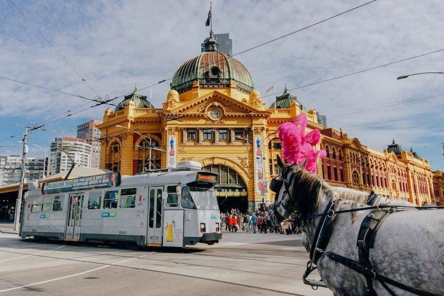 Flinders Street Station in Melbourne. A grand old building with a modern tram passing in front and horse and carriage.