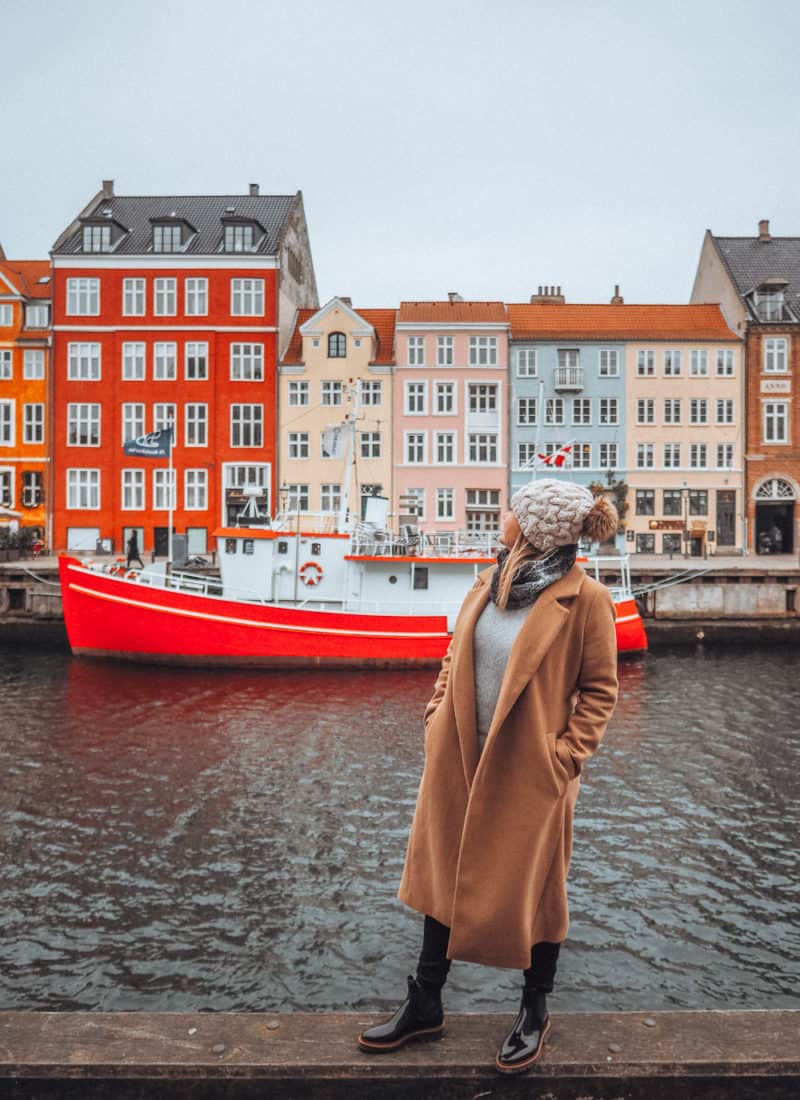 Girl looking over the colourful buildings and boats of Nyhavn