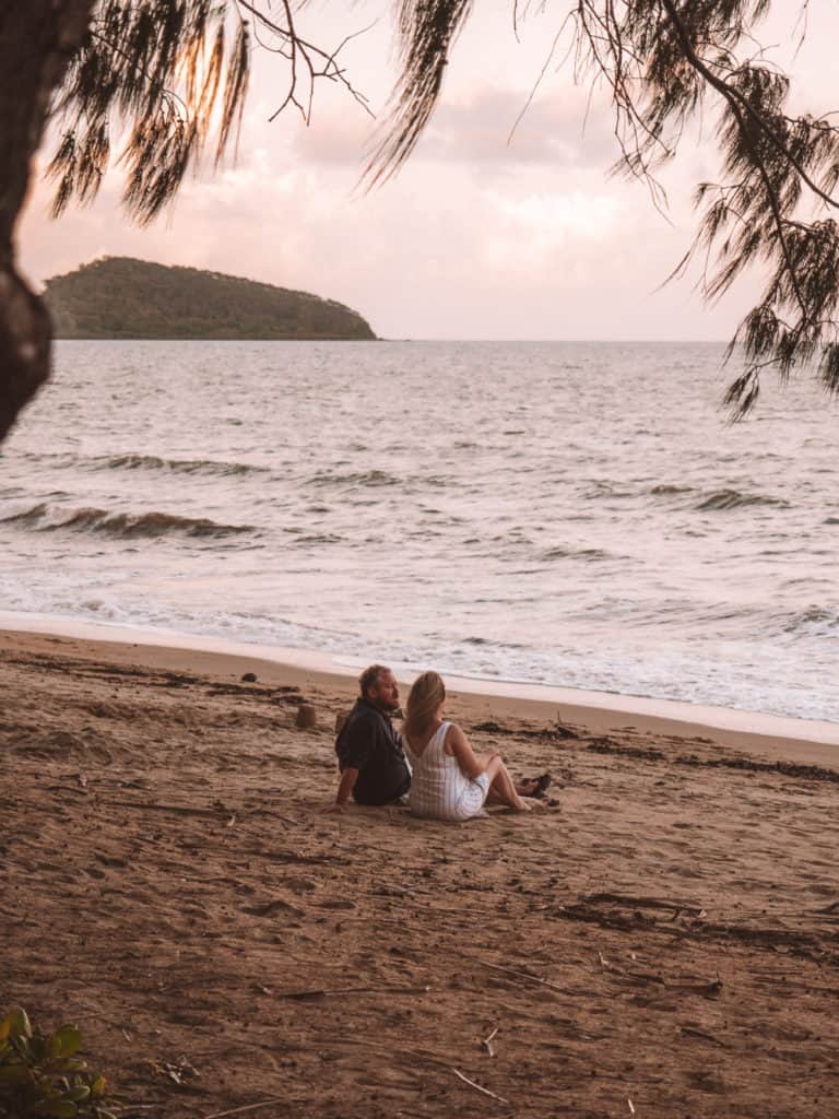 Couple sitting on the beach at sunset in Palm Cove, Australia