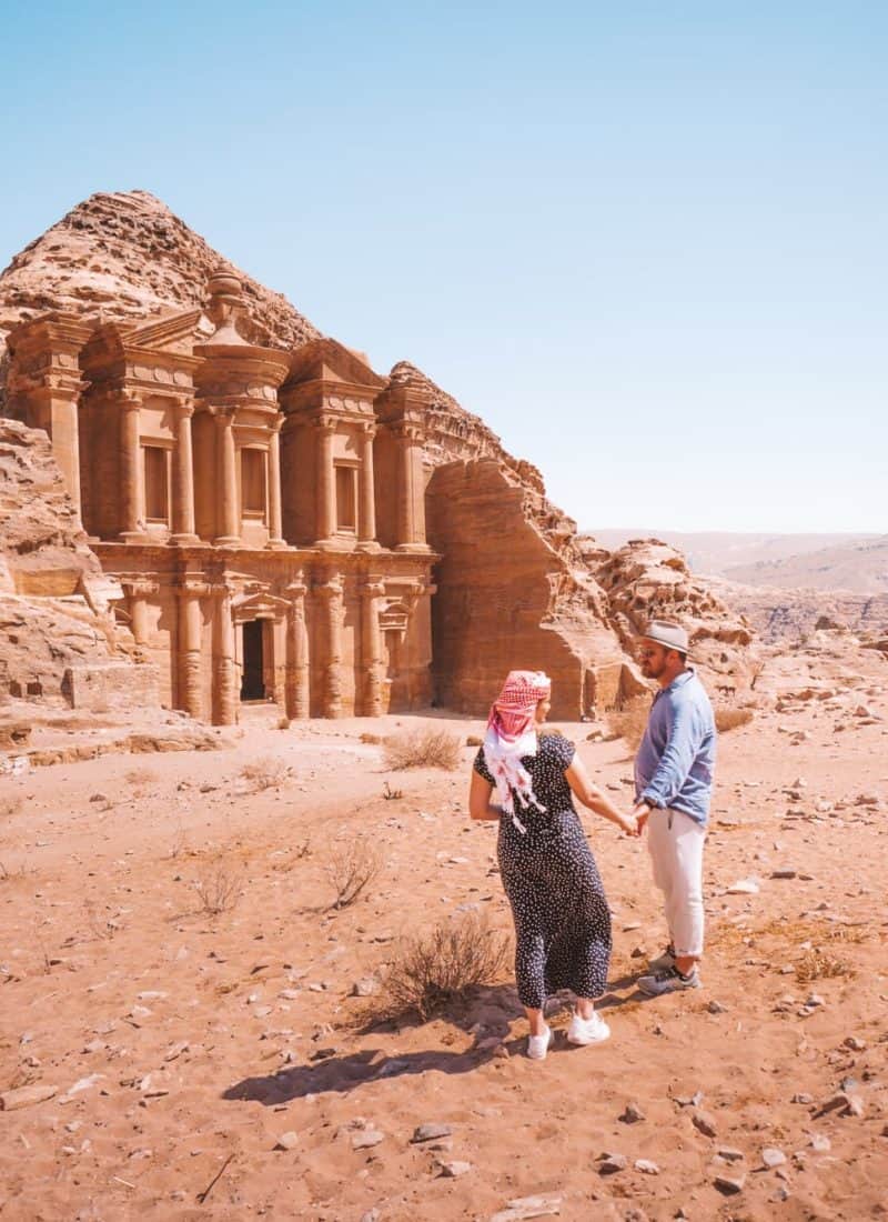 A couple holding hands looking out over the Monastery at Petra, Jordan